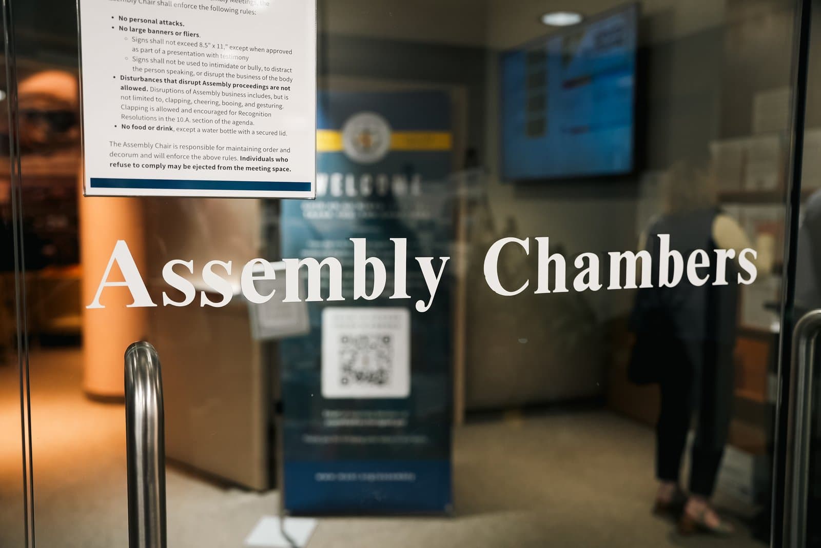 The entrance to the Anchorage Assembly Chambers features a posted list of meeting rules on a glass door.