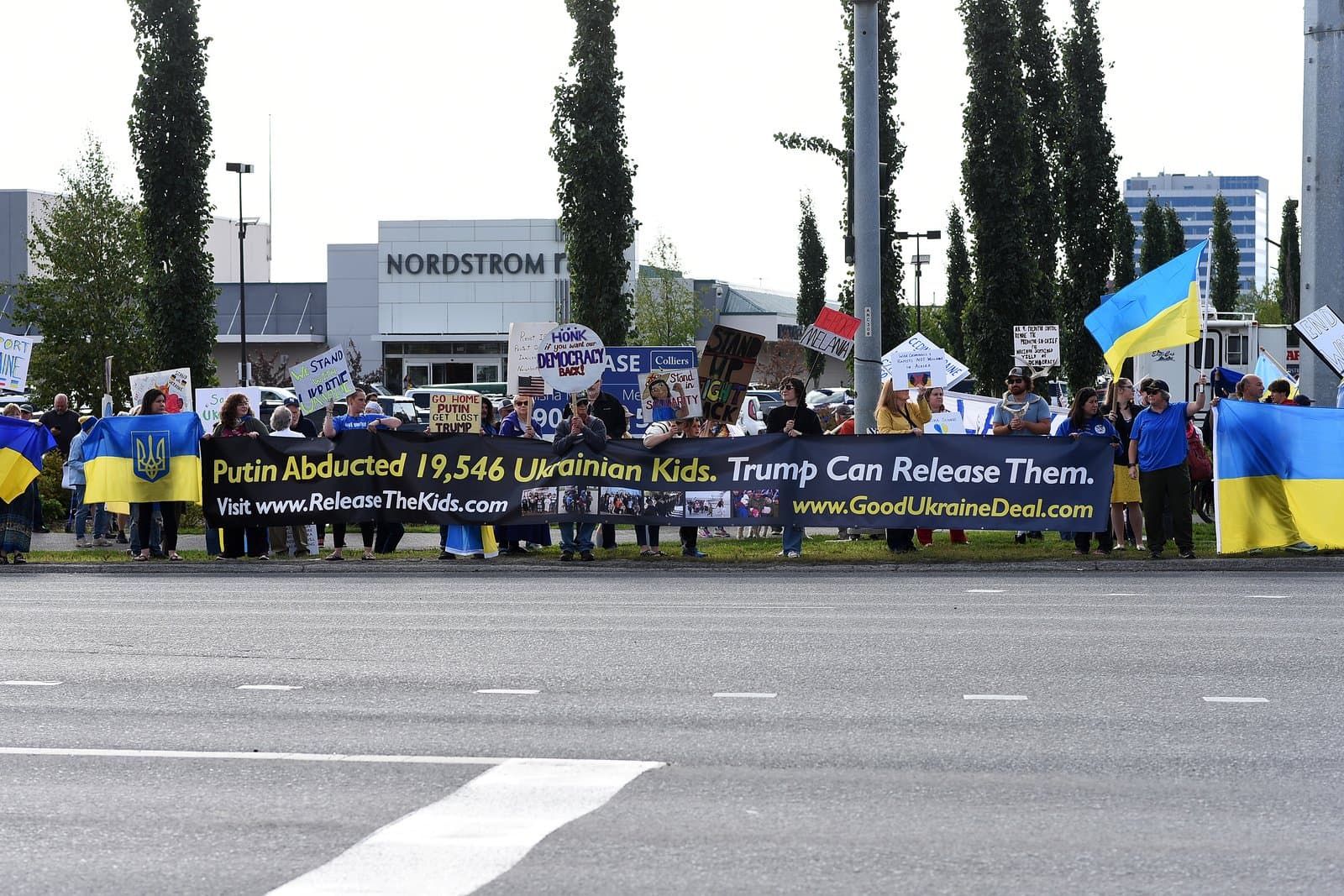 Protesters hold a banner demanding the release of Ukrainian children outside a Nordstrom store in midtown Anchorage on August 14, 2025.
