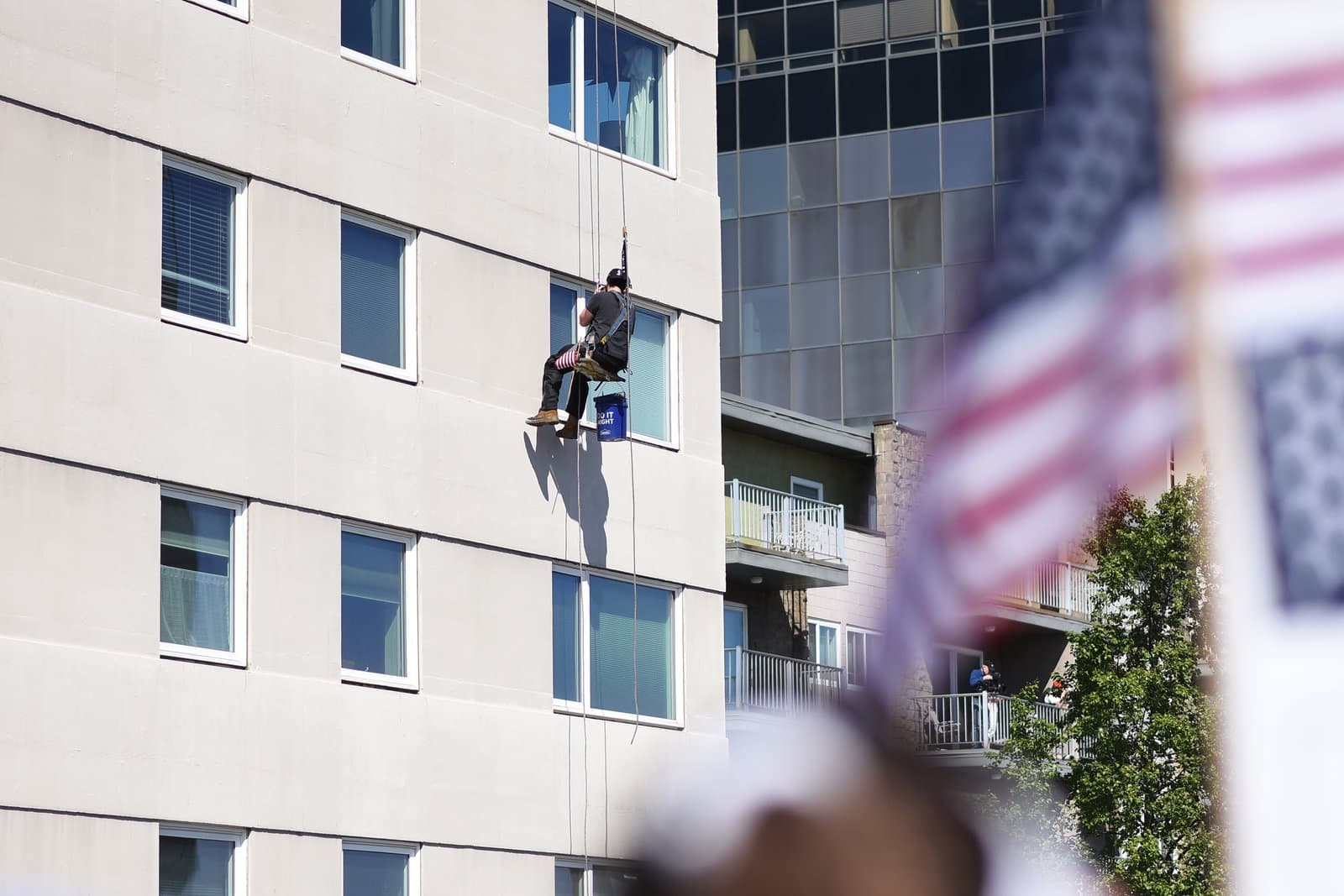 A window washer suspended on a high-rise building continues working during a "No Kings" protest in downtown Anchorage, Alaska.