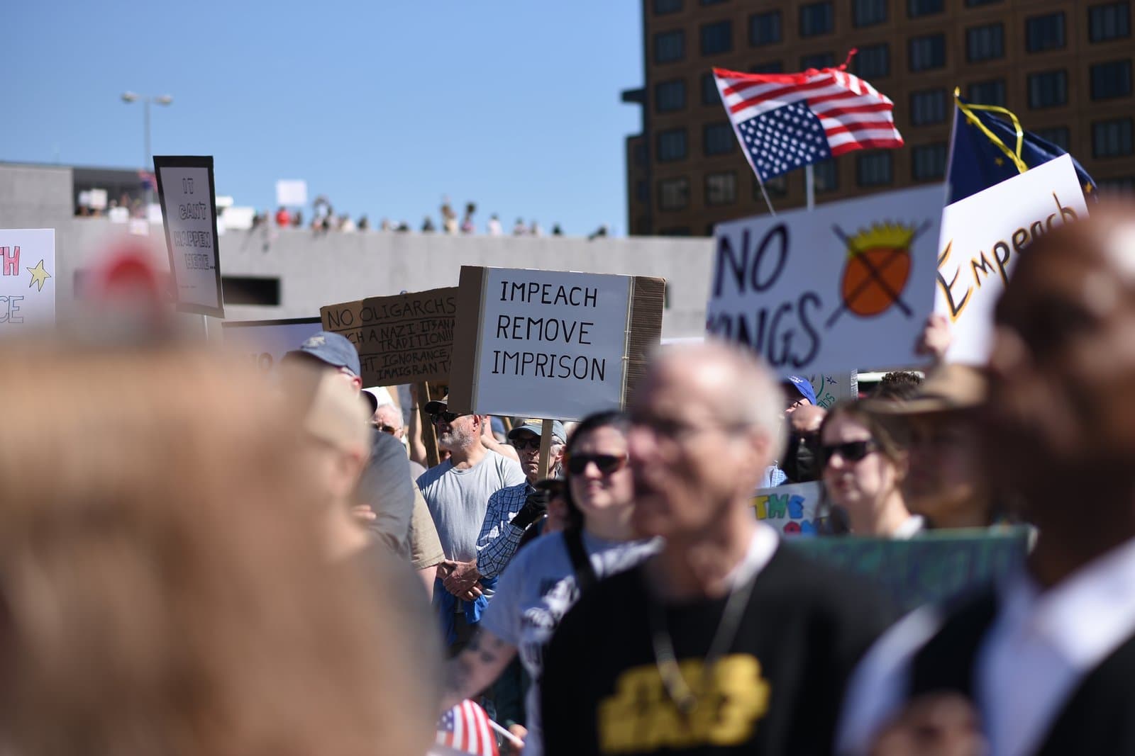Protesters hold signs advocating for impeachment and removal during a public demonstration in Anchorage, Alaska, on June 14, 2025.