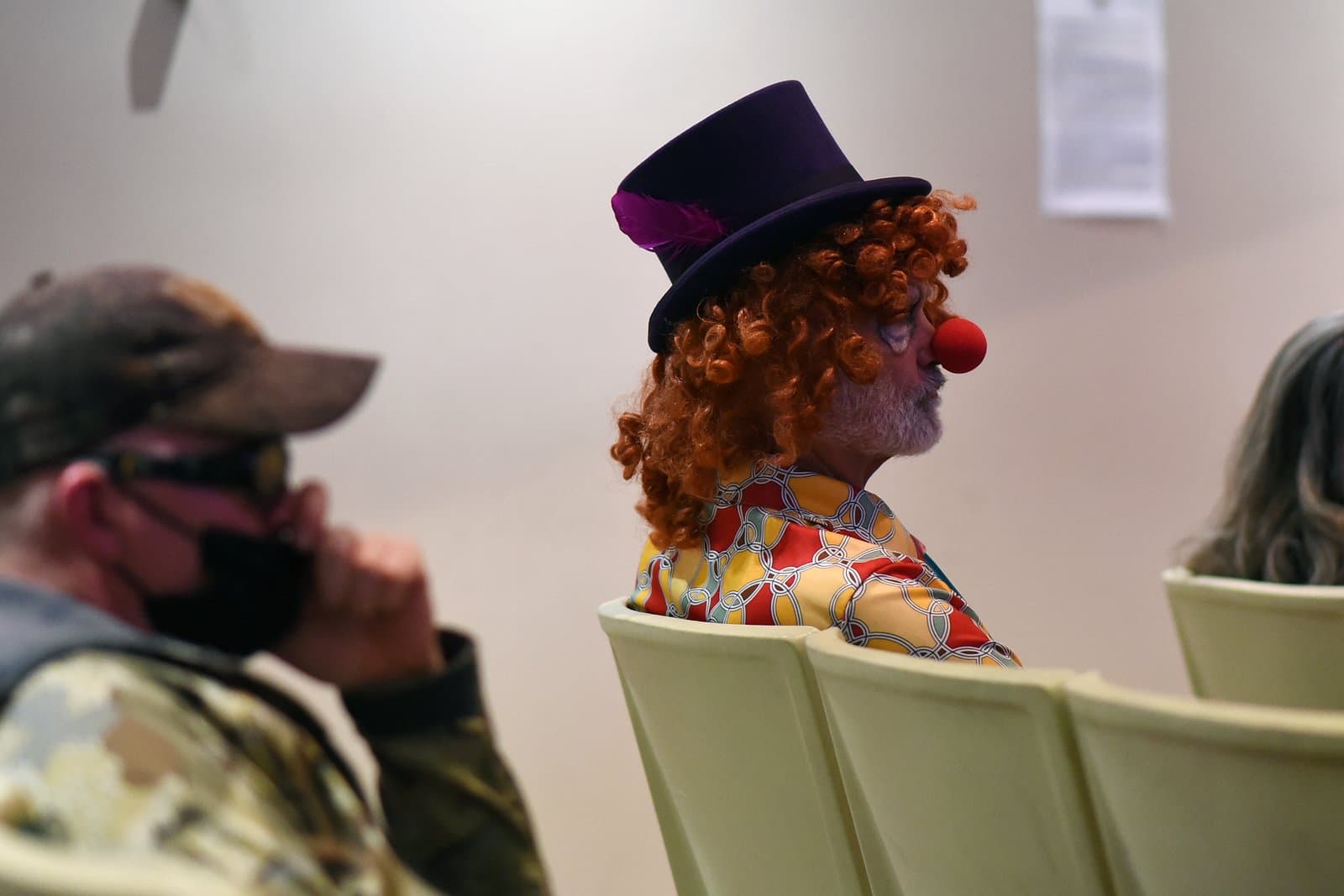 A person dressed as a clown sits in a chair during an Anchorage Assembly meeting held in July 2022.