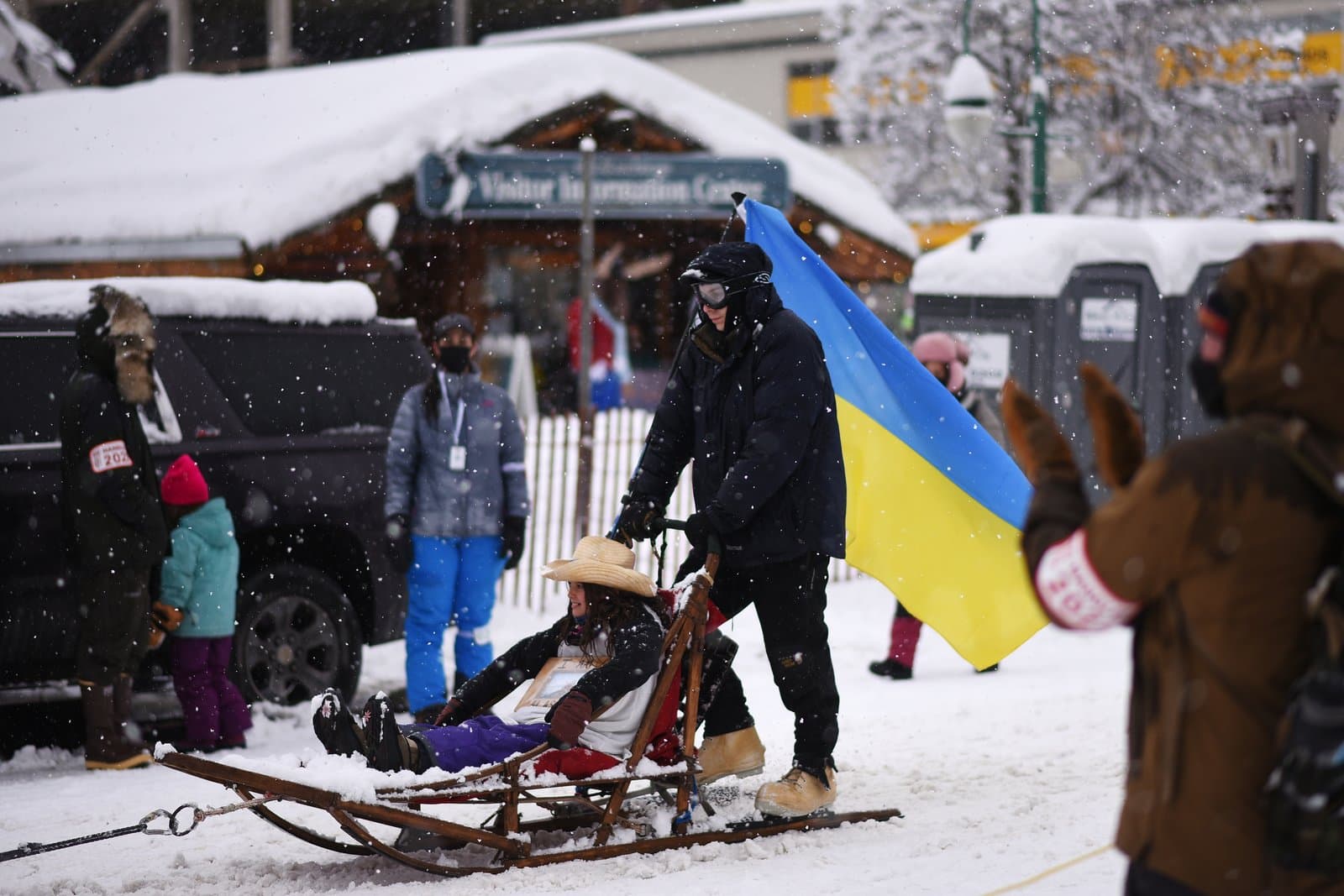 A person pulls a sled carrying a child in a straw hat during the 2022 Iditarod ceremonial start in downtown Anchorage, Alaska.