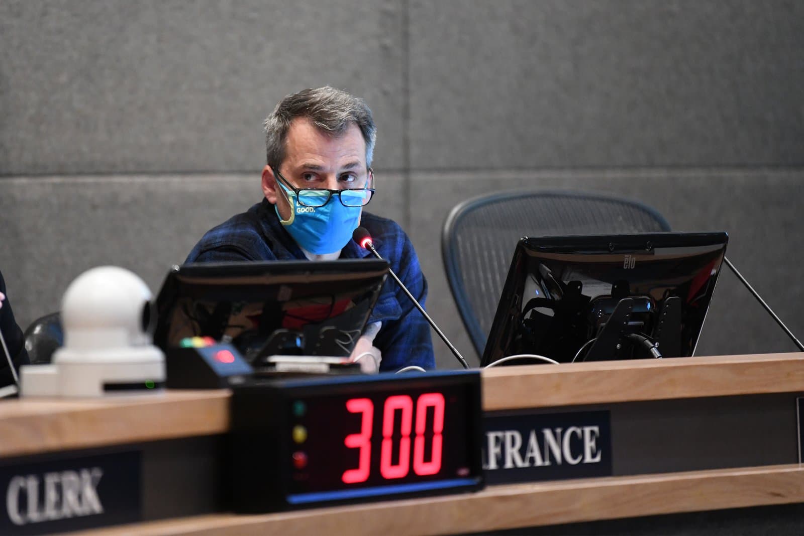 An Anchorage Assembly member wearing a blue face mask speaks into a microphone during a public meeting in Anchorage, Alaska.