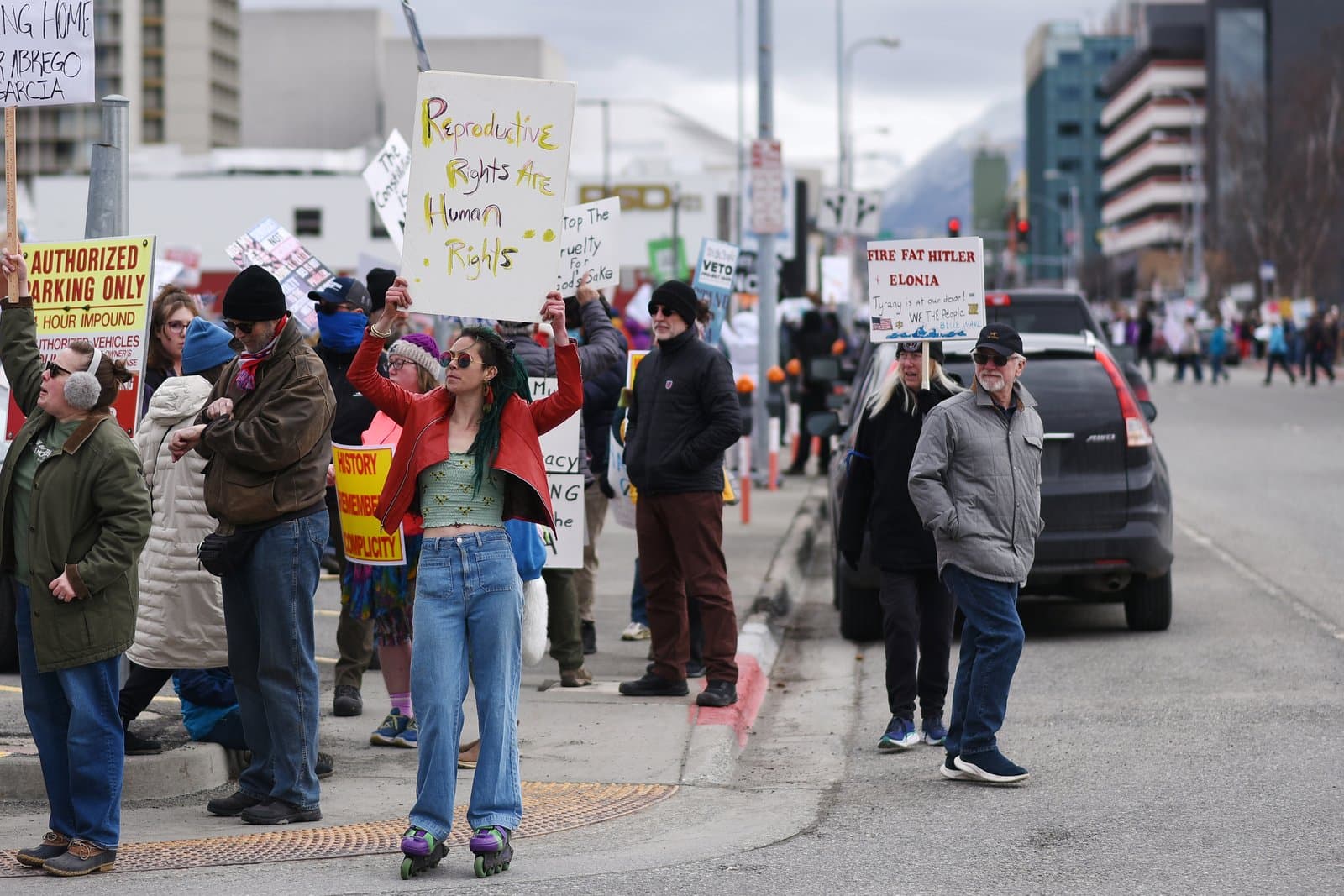 Protesters hold signs advocating for reproductive rights while walking along a sidewalk in Anchorage during an April 2025 demonstration.