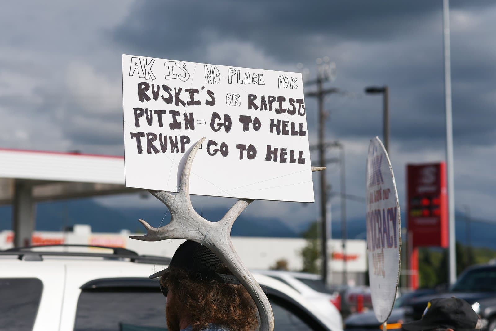 A protest sign featuring political slogans is held up by an individual at a pro-Ukraine and anti-Trump rally in midtown Anchorage.