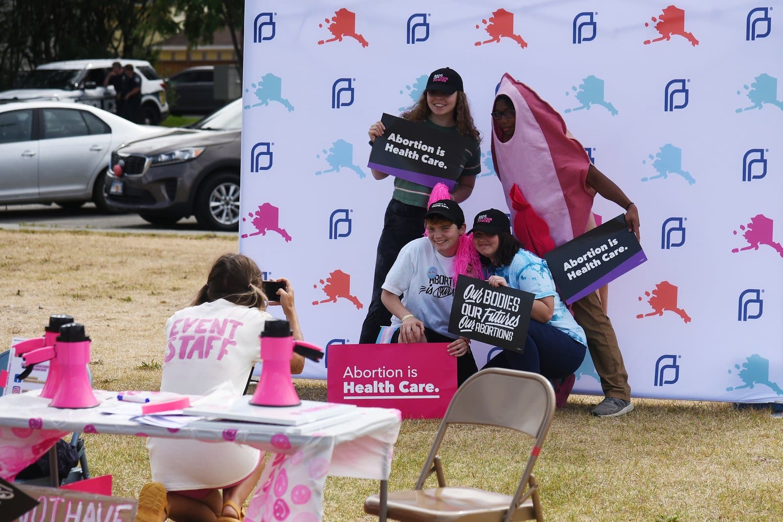 Participants hold signs supporting reproductive rights during a Planned Parenthood rally in downtown Anchorage, Alaska, on a sunny summer day.
