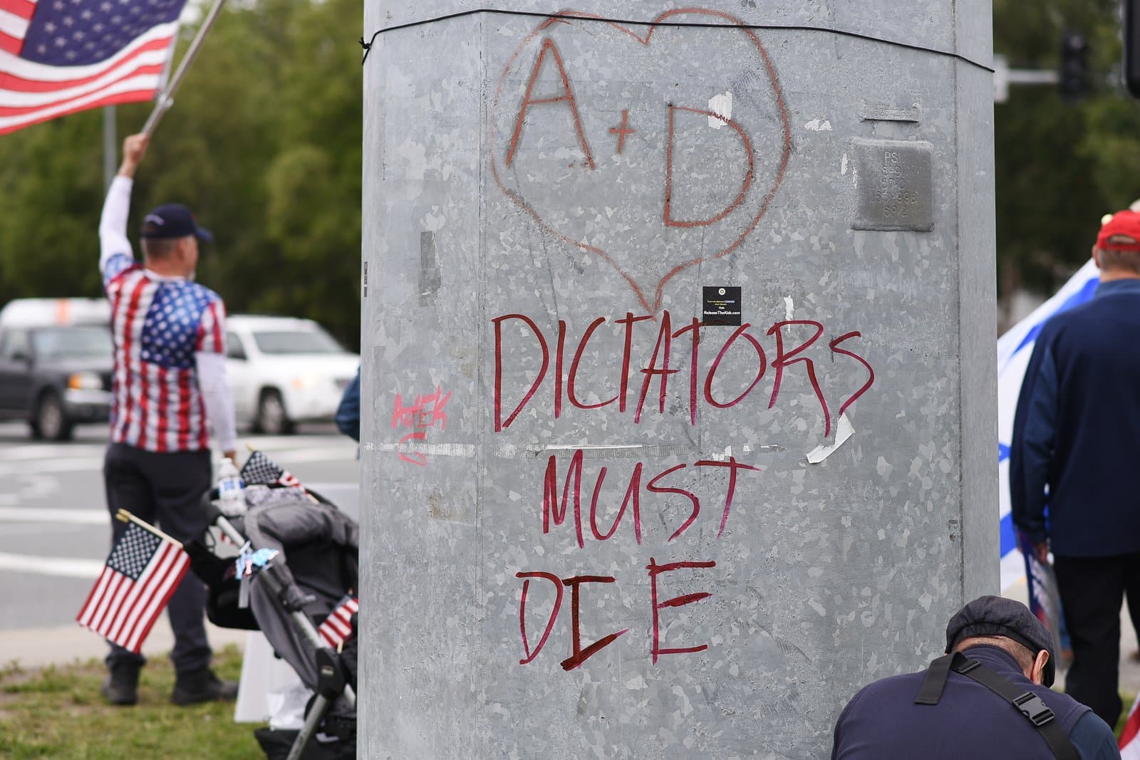 A utility pole in midtown Anchorage features hand-drawn graffiti with a heart and the message, Dictators Must Die, during a political rally.