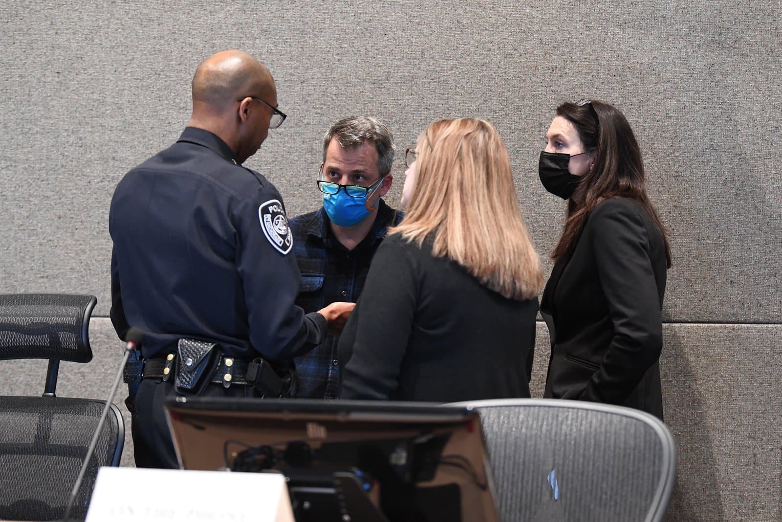 A police officer speaks with three individuals during an Anchorage Assembly meeting held in October 2021 in Anchorage, Alaska.