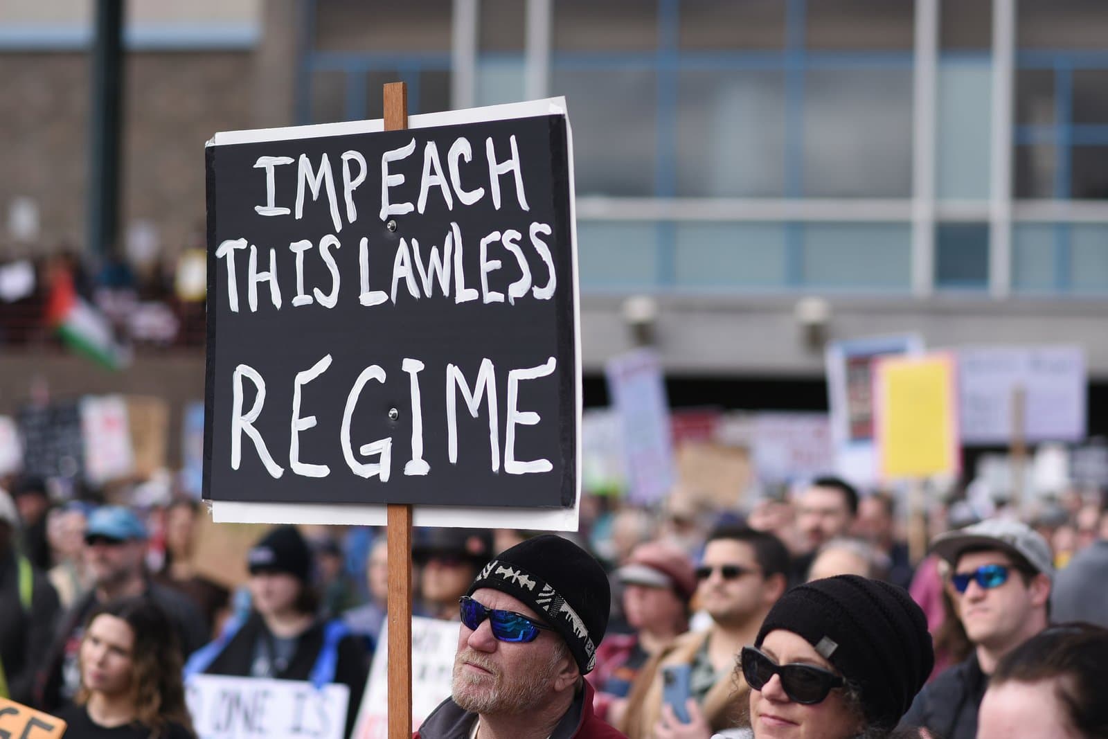 Protesters hold a sign reading Impeach This Lawless Regime during a public demonstration in Anchorage, Alaska, on April 19, 2025.