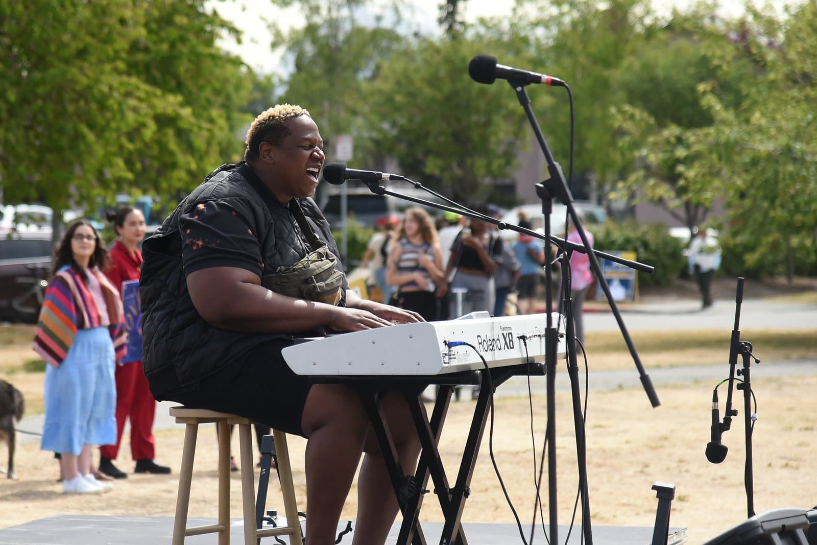 A musician plays a Roland Fantom keyboard while singing into a microphone during a Planned Parenthood rally in downtown Anchorage, Alaska.