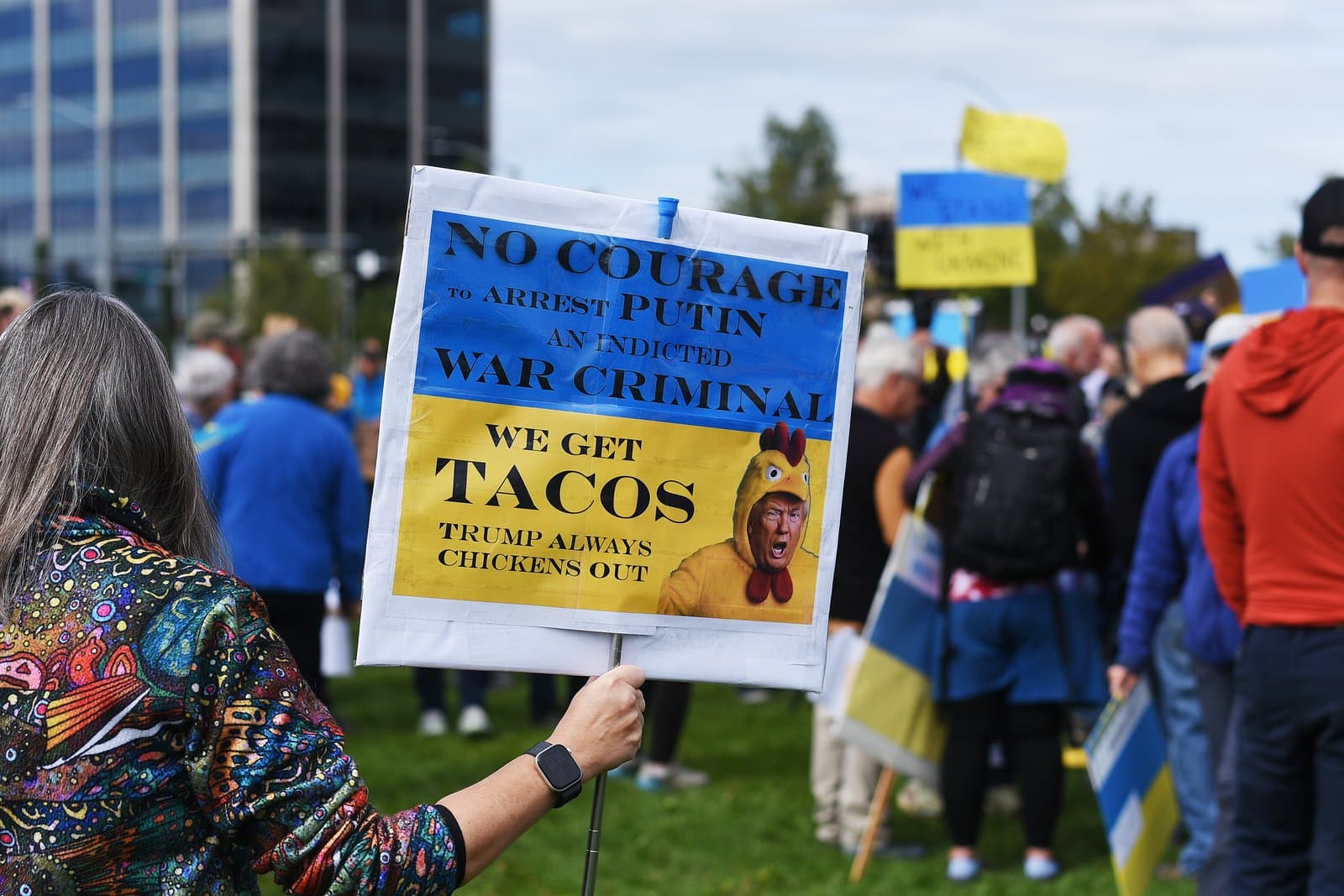 A protest sign featuring a caricature of Donald Trump in a chicken suit is held during a pro-Ukraine demonstration in downtown Anchorage.