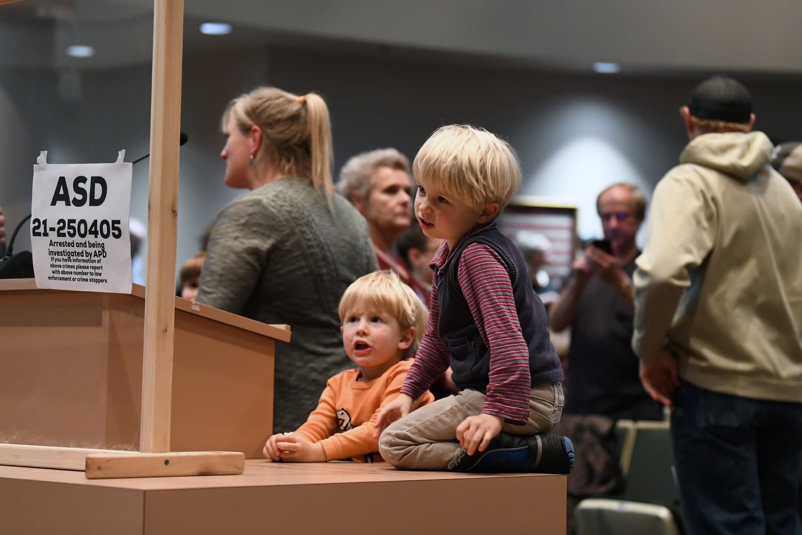 Two young children sit on a wooden podium during an Anchorage Assembly meeting held in October 2021.