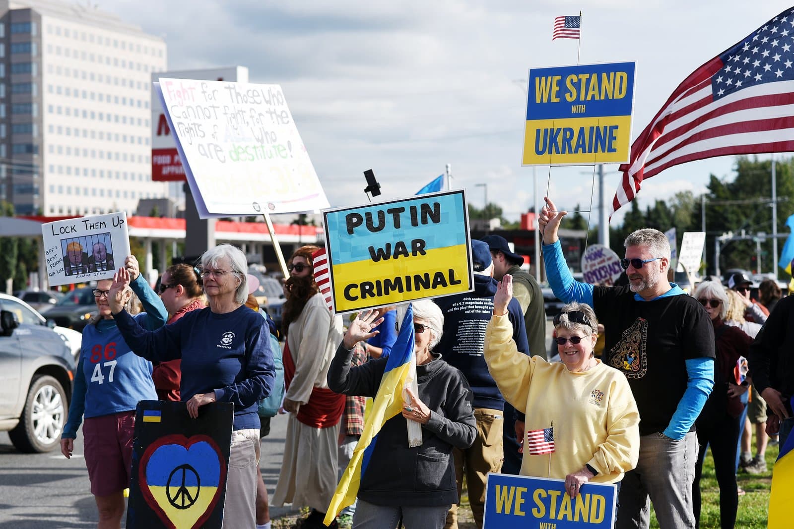 Protesters hold signs supporting Ukraine and criticizing political figures during a public rally in midtown Anchorage, Alaska, in August 2025.