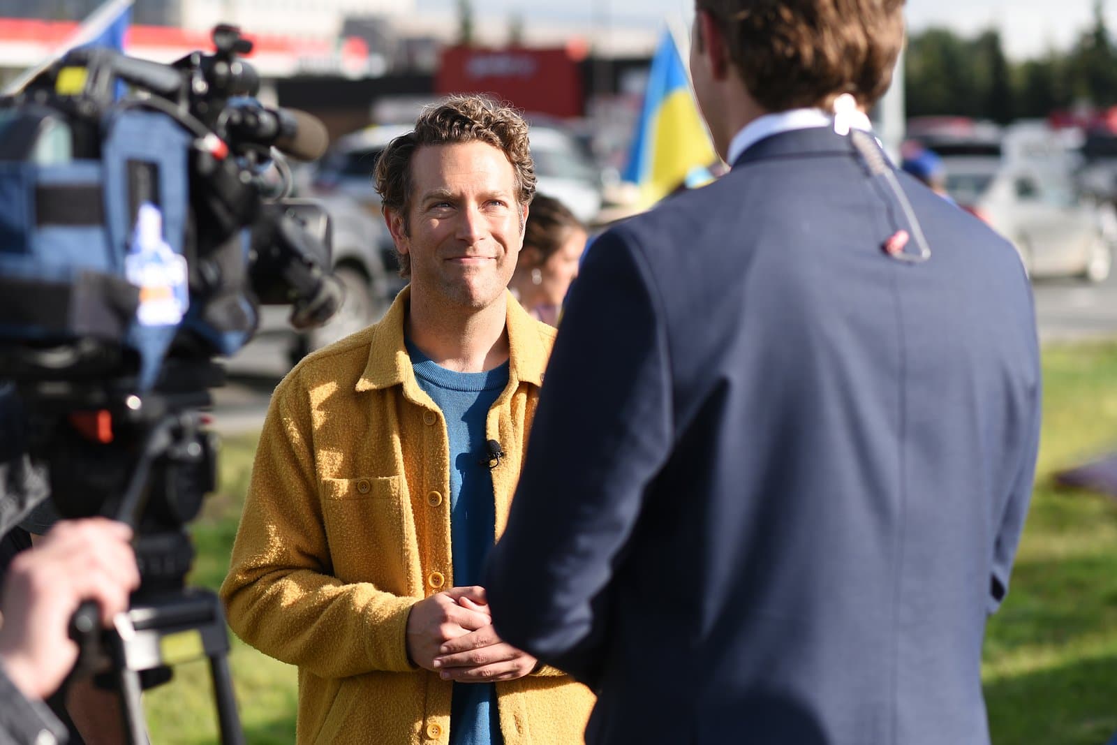 A reporter interviews a man wearing a yellow jacket during a pro-Ukraine rally and anti-Trump protest in midtown Anchorage, Alaska.