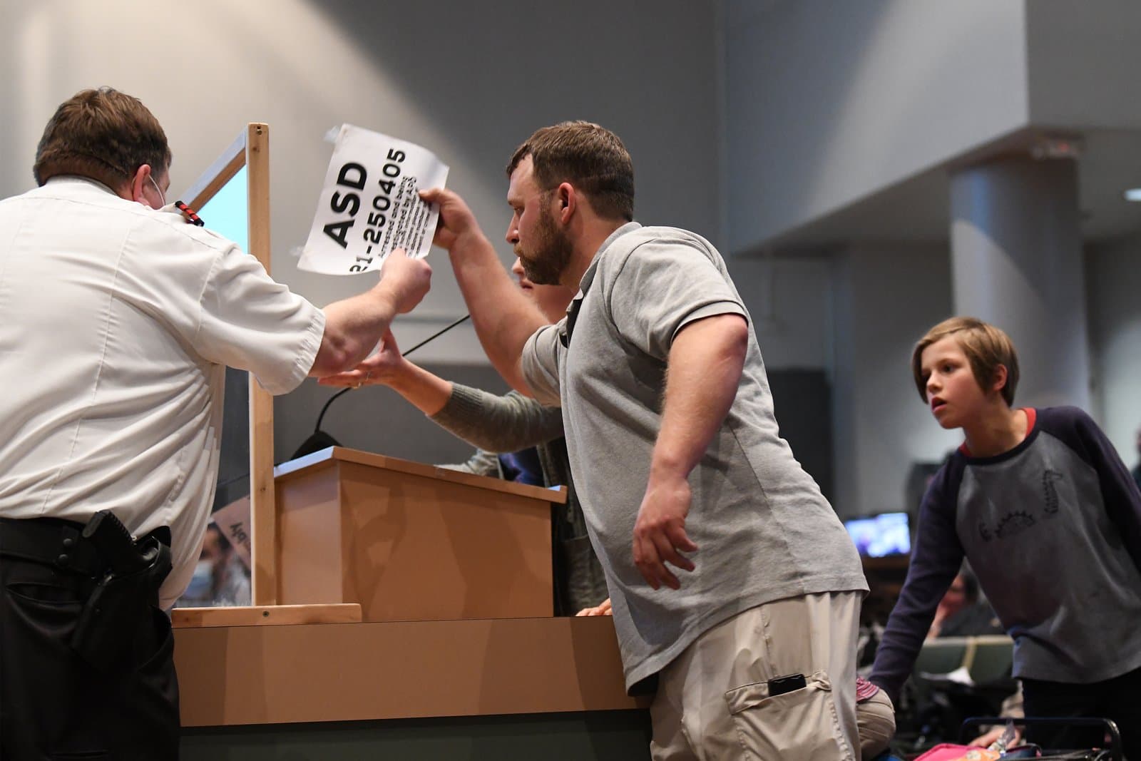 A man holds up a document labeled ASD 21-250405 while speaking at an Anchorage Assembly meeting in October 2021.