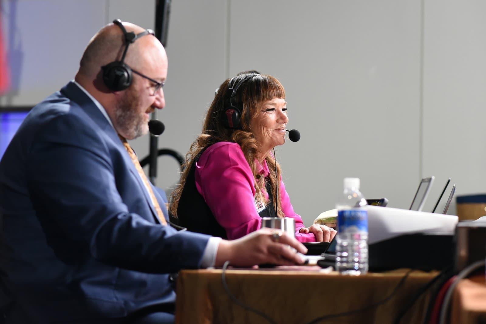 Two broadcasters wearing headsets work at a desk during an Election Central event in November 2024, with laptops and a water bottle visible.