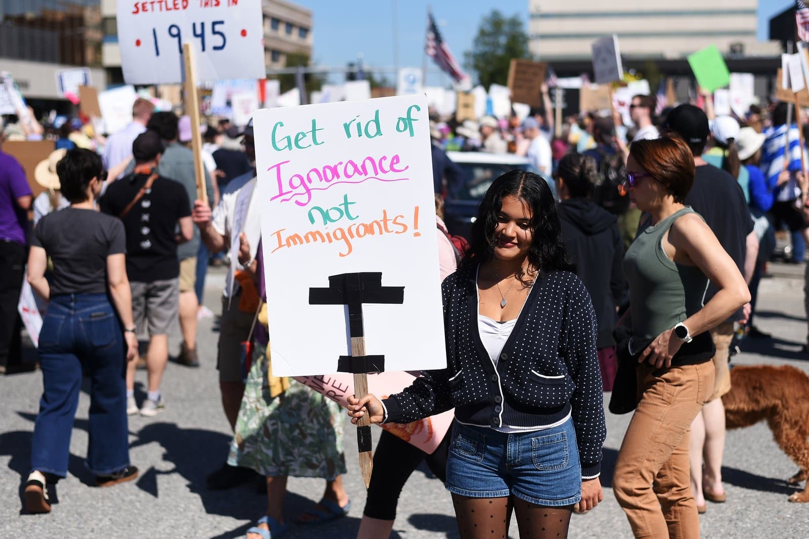 A young woman holds a protest sign reading Get rid of Ignorance not Immigrants during the No Kings demonstration in Anchorage, Alaska.
