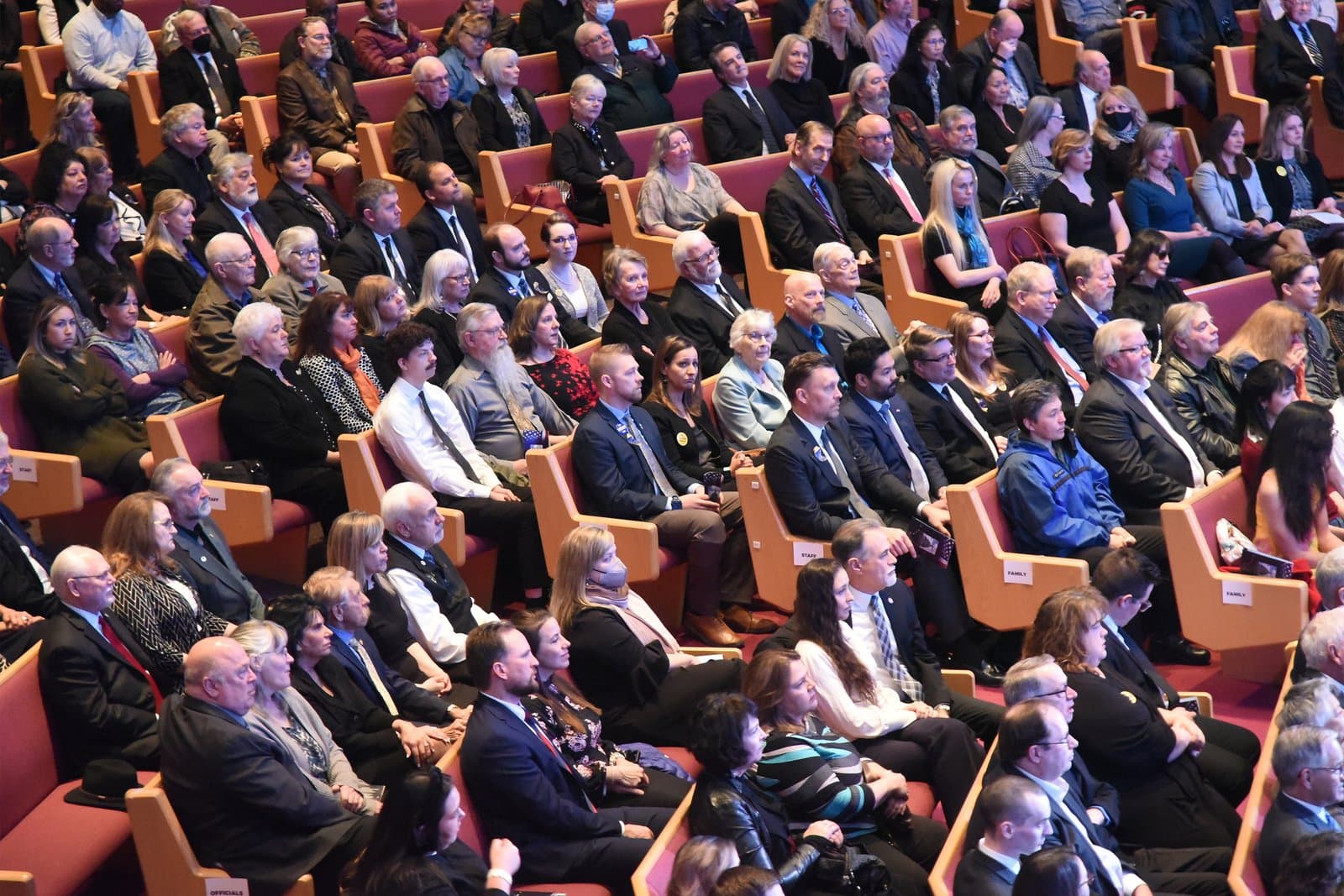 Attendees sit in rows of wooden pews during the memorial service for Congressman Don Young held in an auditorium.