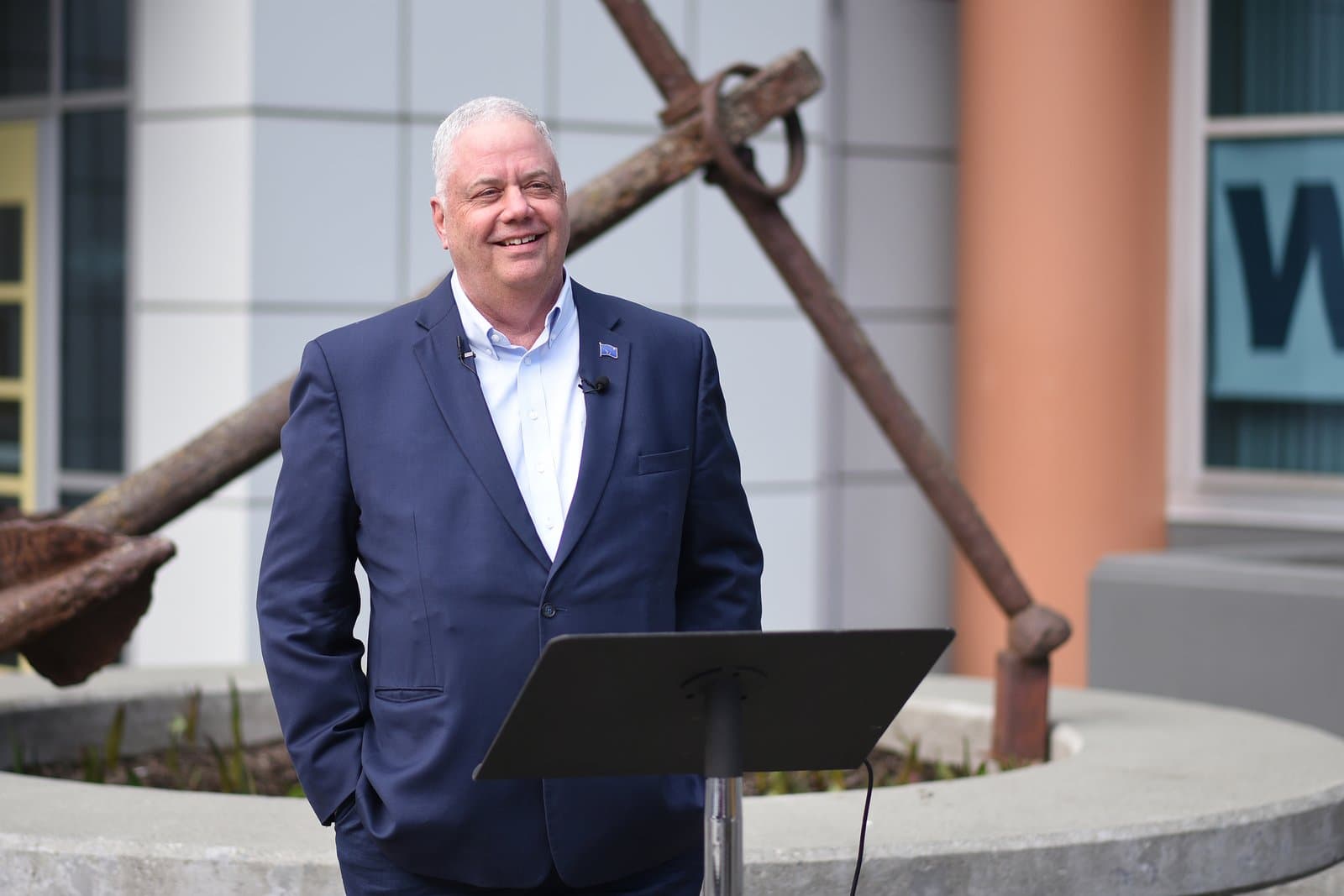Bill Popp stands at a podium outdoors in Anchorage, Alaska, during an event endorsing Suzanne LaFrance for public office.