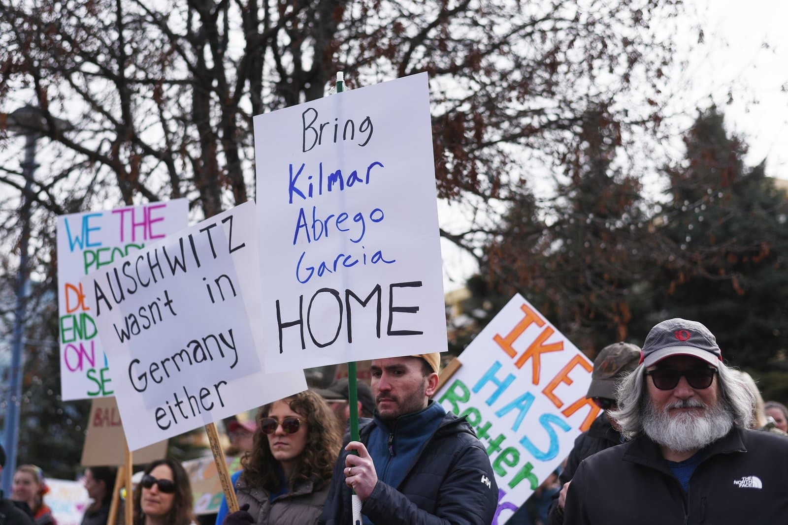 Protesters hold signs with political messages during a demonstration in Anchorage, Alaska, on a cloudy spring day in April 2025.