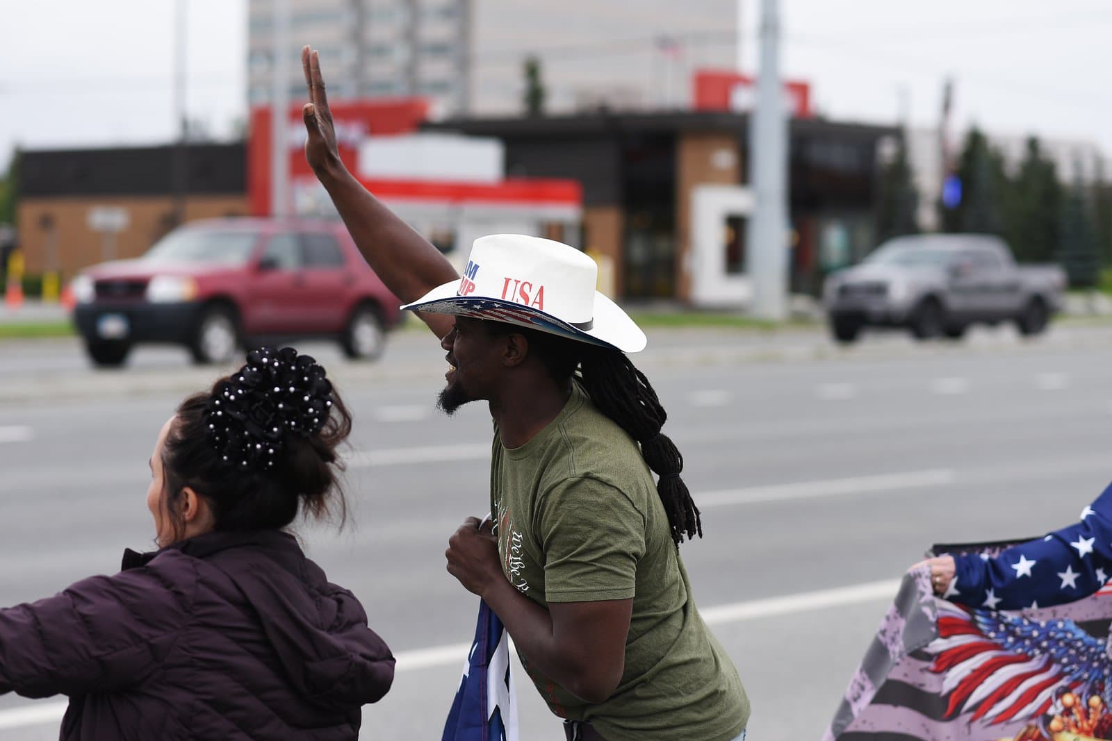 A man wearing a USA cowboy hat waves to traffic during a pro-Trump rally held in midtown Anchorage on August 15, 2025.