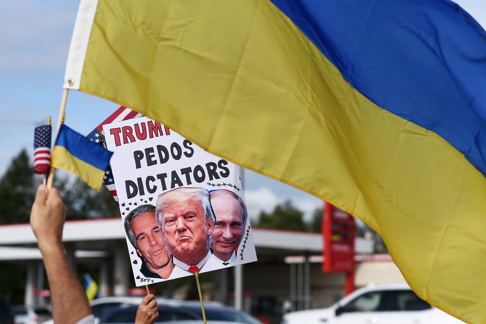 A protester holds a sign depicting Donald Trump, Vladimir Putin, and Jeffrey Epstein during a pro-Ukraine rally in midtown Anchorage, Alaska.