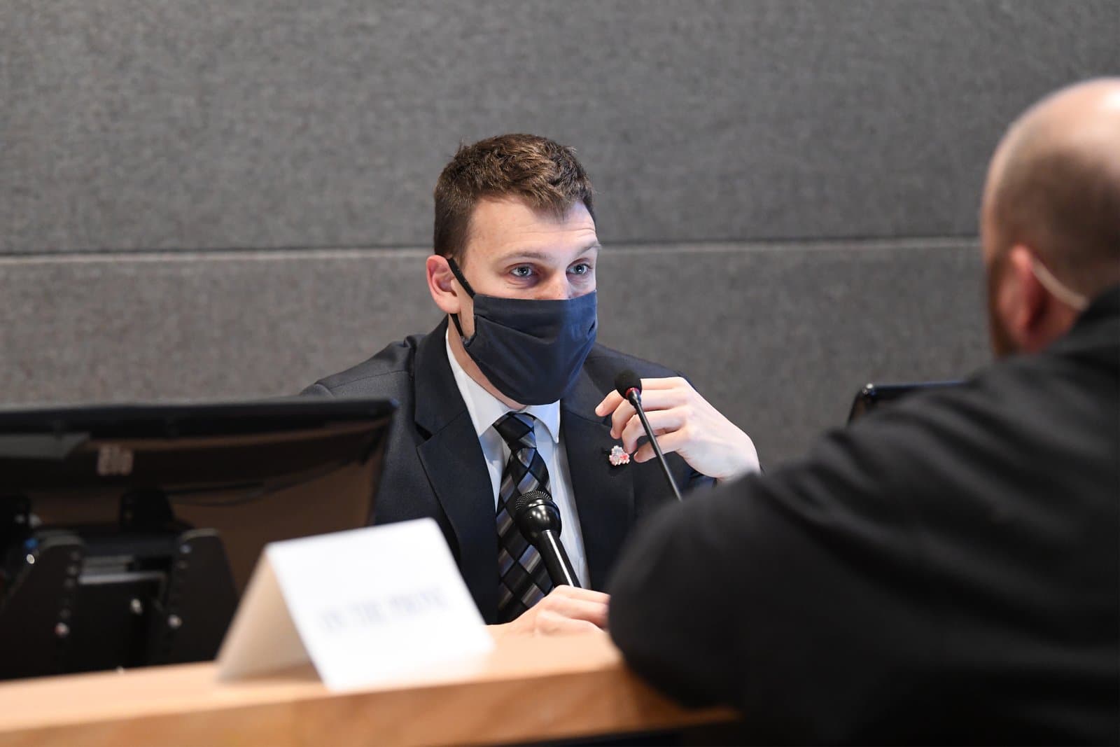 An Anchorage Assembly member wearing a face mask speaks into a microphone during a public meeting held in Anchorage, Alaska.