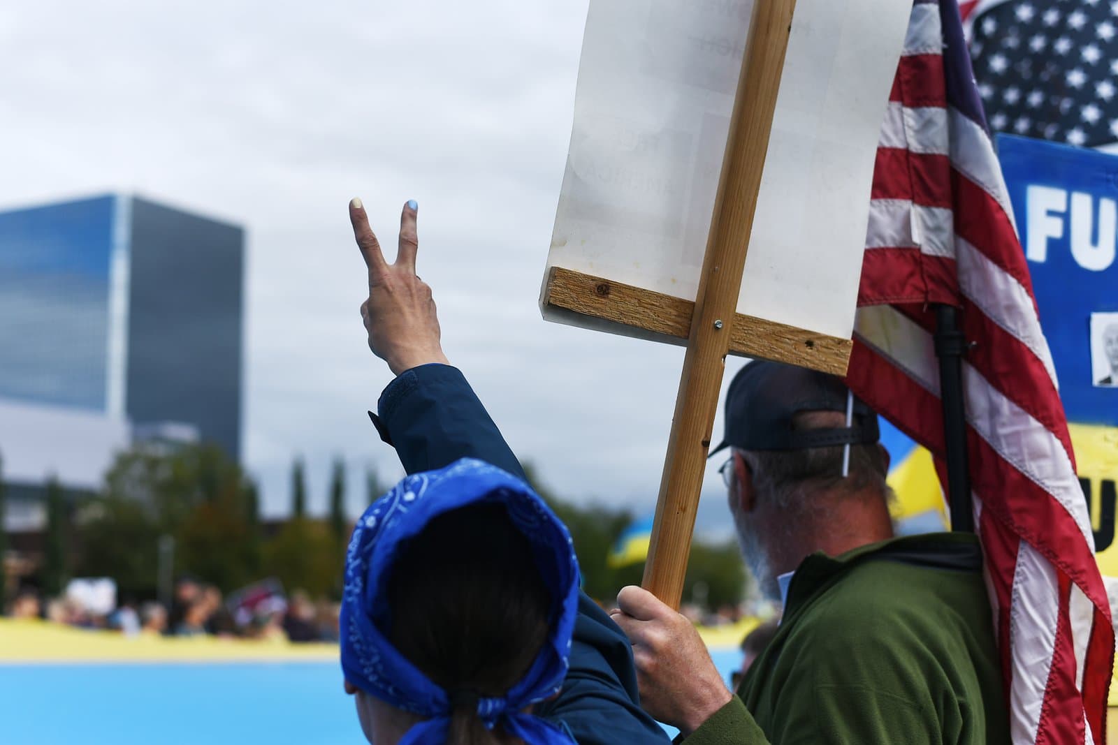 Protesters hold signs and an American flag during a pro-Ukraine demonstration in downtown Anchorage on a summer afternoon.