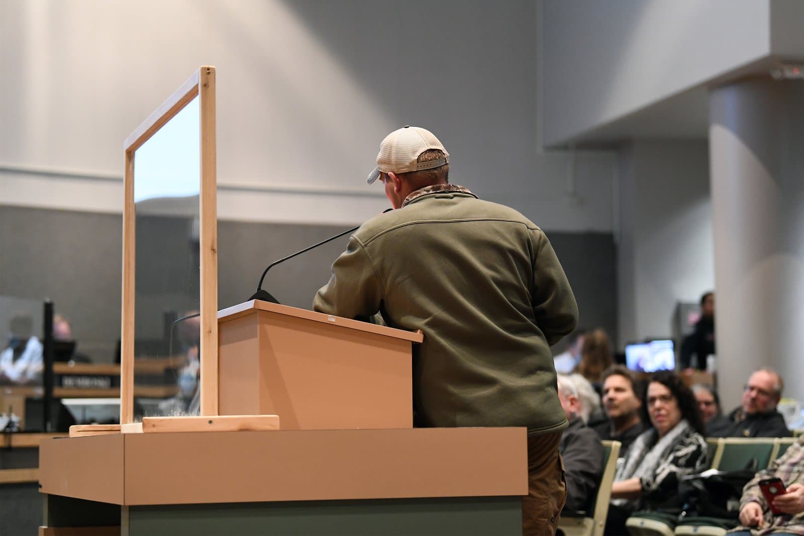 A resident wearing a baseball cap speaks into a microphone at a podium during an Anchorage Assembly meeting in October 2021.
