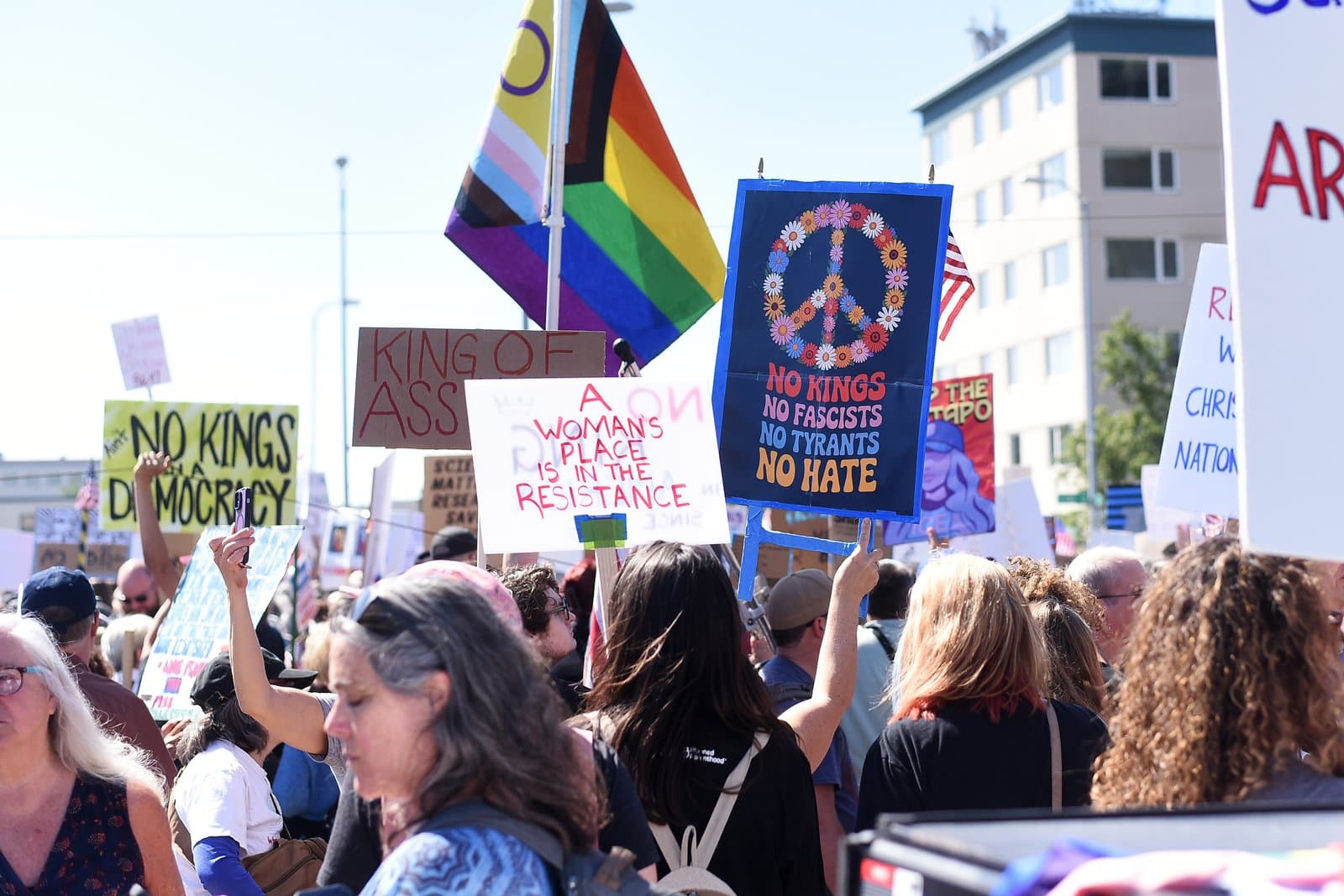 Protesters hold signs and flags during a demonstration in Anchorage, Alaska, on June 14, 2025, advocating for democratic principles.
