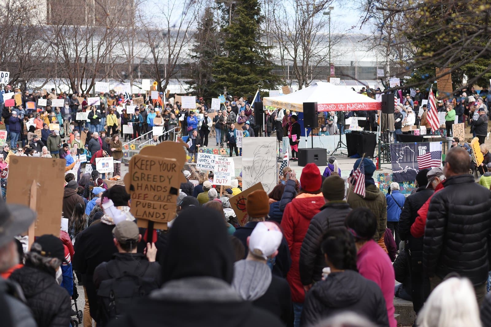 A crowd of protesters gathers in an Anchorage park for a rally advocating for the protection of public lands in Alaska.