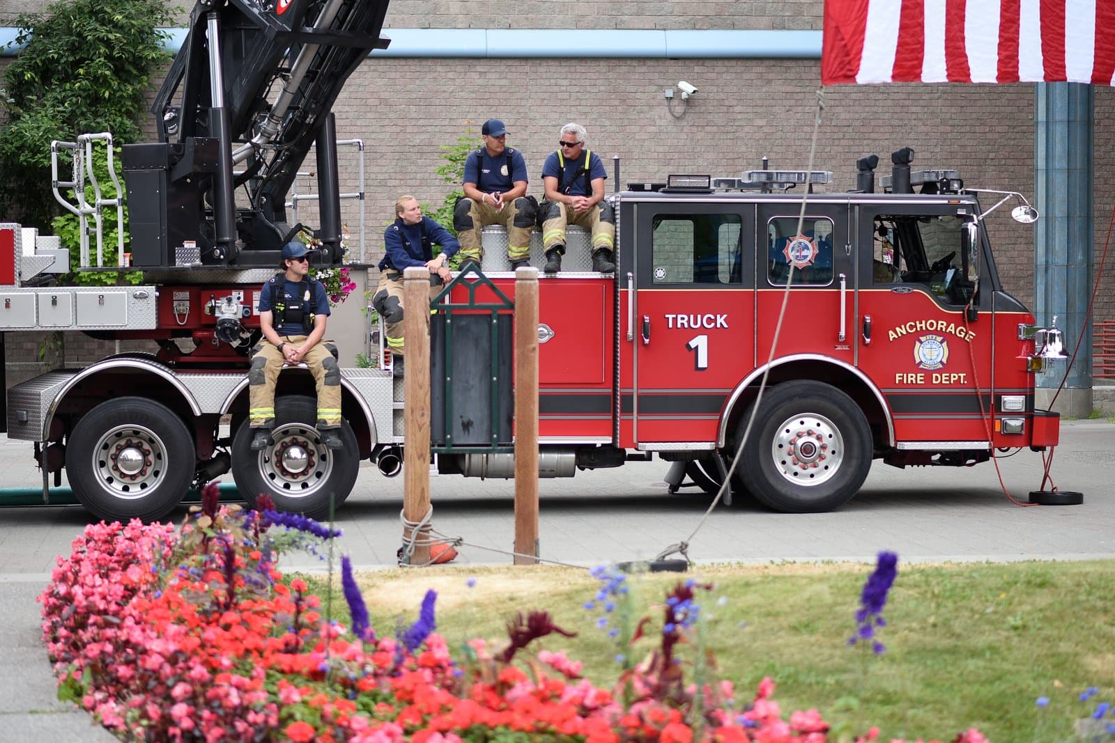 Four Anchorage Fire Department firefighters sit on a red fire truck during the LaFrance inauguration ceremony in Anchorage, Alaska.