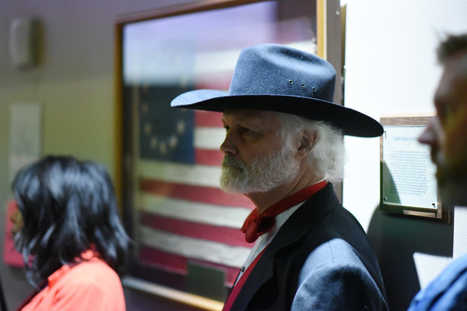 A man wearing a wide-brimmed hat and red neckerchief stands in profile during an Anchorage Assembly meeting in October 2021.