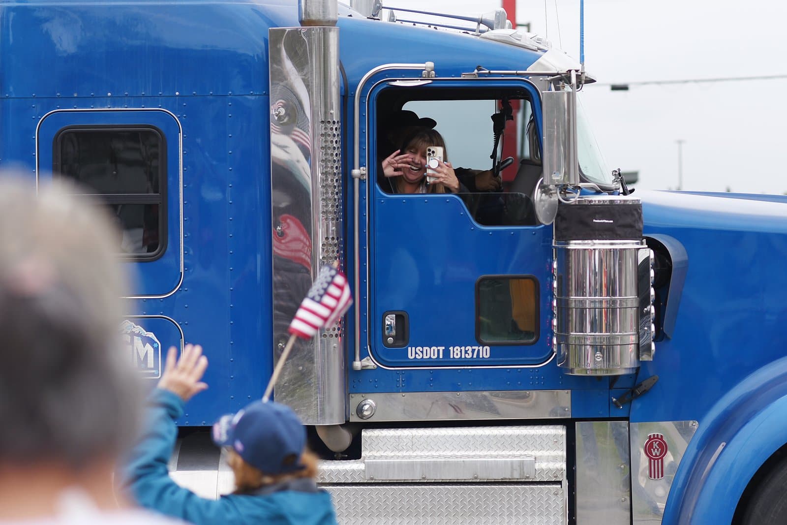 A truck driver waves from the cab of a blue semi-truck during a pro-Trump rally in midtown Anchorage, Alaska.