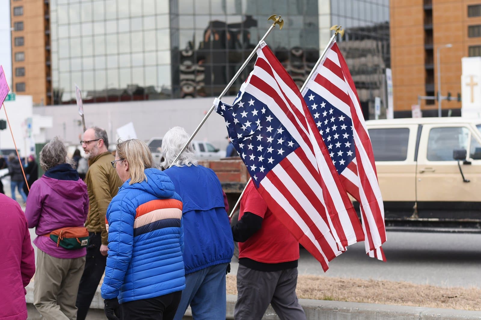 Protesters carry American flags while walking along a street during a public demonstration in Anchorage, Alaska, on April 19, 2025.