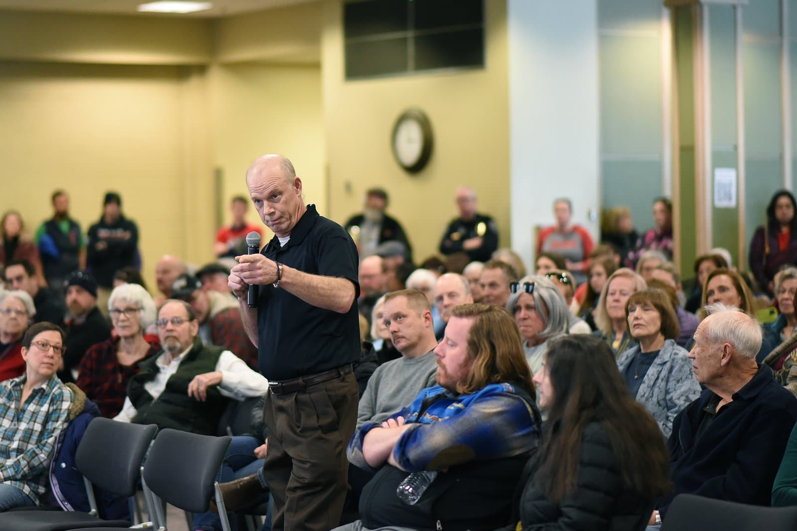A man speaks into a microphone while addressing an audience during the 2024 Anchorage Legislative Town Hall meeting.