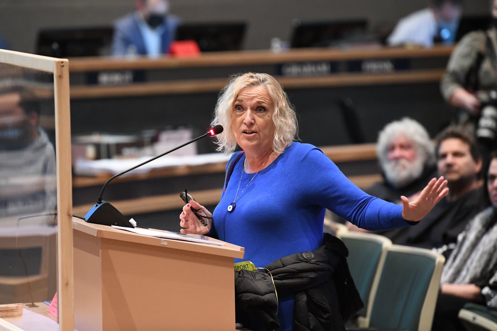 A woman with blonde hair speaks into a microphone at a podium during an Anchorage Assembly meeting in October 2021.