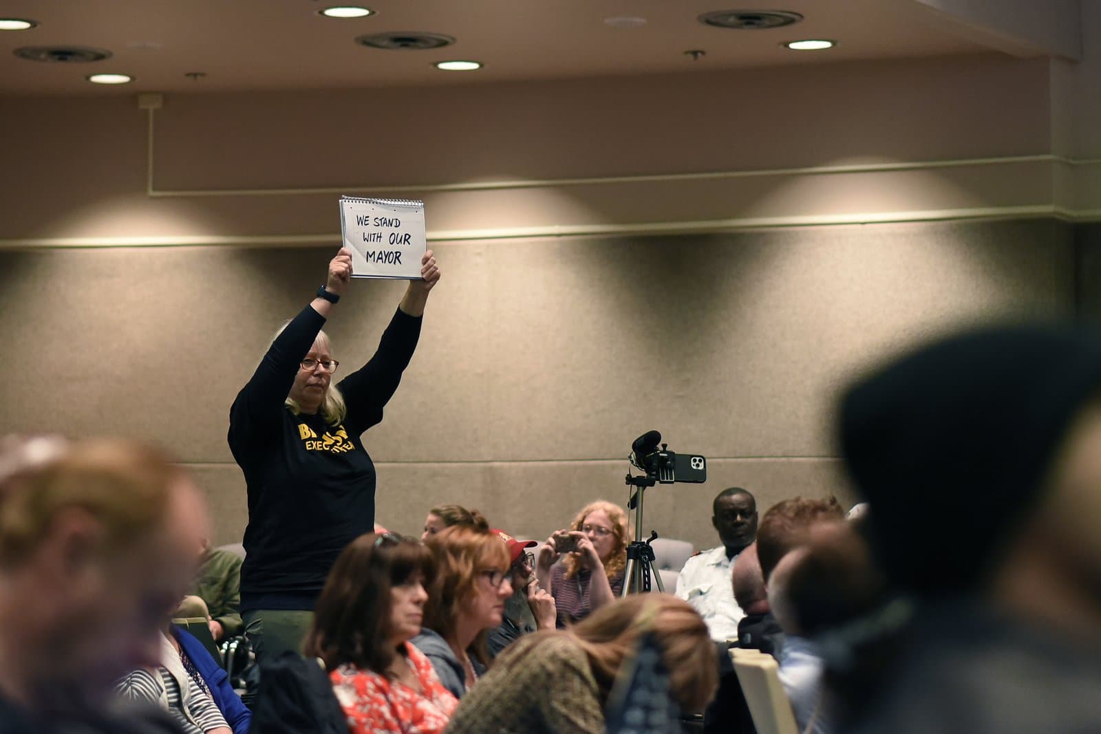 A woman holds a sign reading We Stand With Our Mayor during an Anchorage Assembly meeting in Anchorage, Alaska, on July 12, 2022.