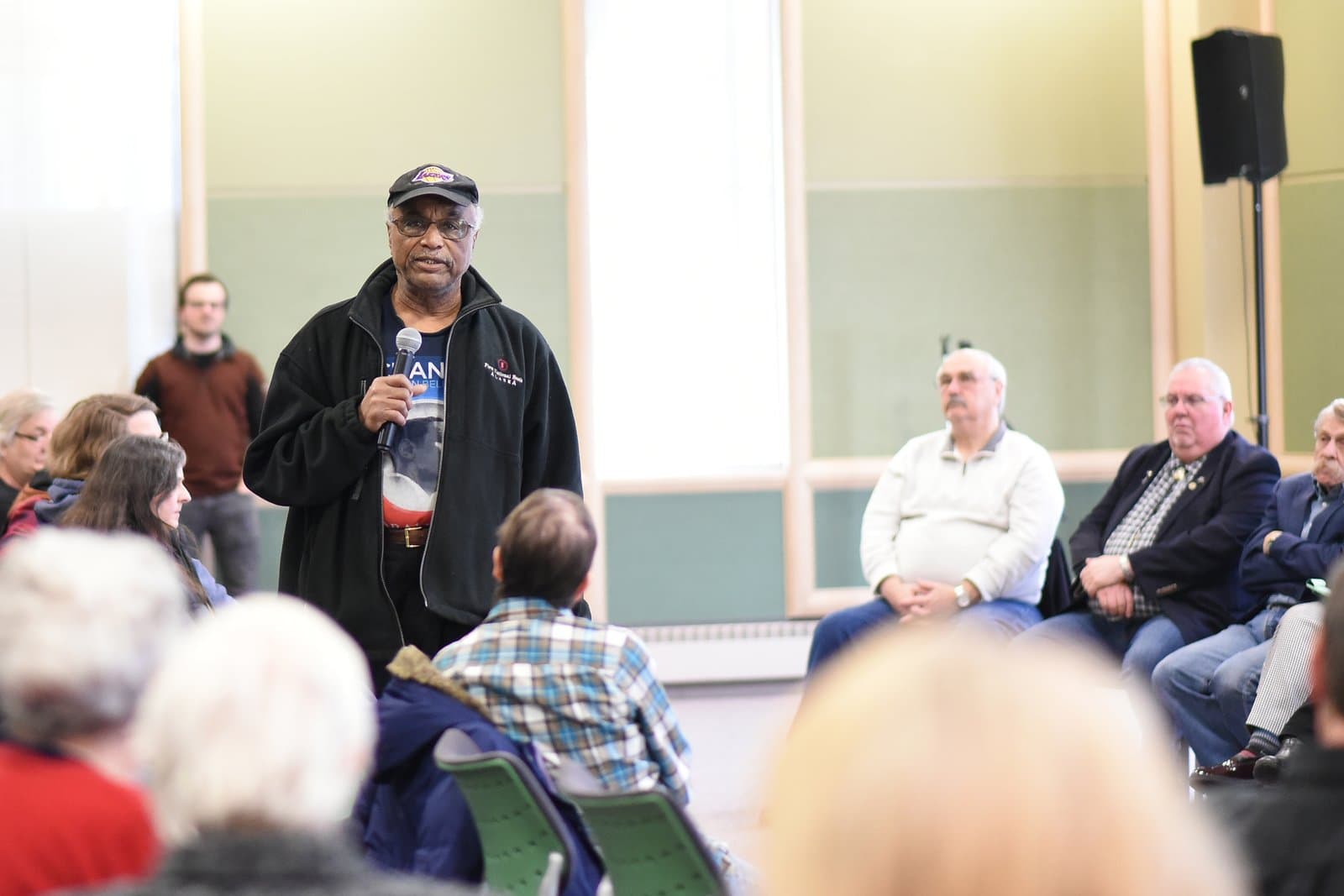 A man speaks into a microphone at an Anchorage legislative town hall meeting held in a community space in March 2024.