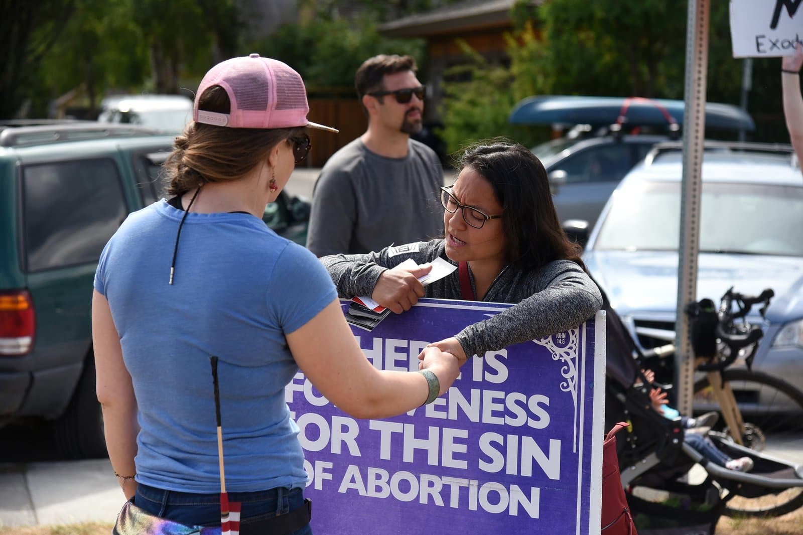 Two women engage in a conversation while holding a sign about abortion during a Planned Parenthood rally in downtown Anchorage, Alaska.