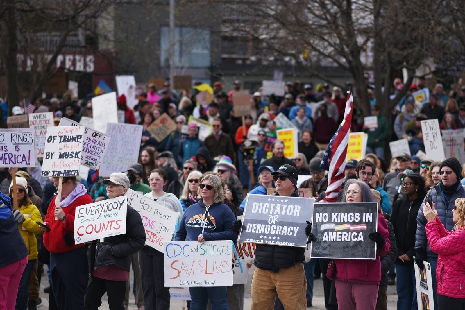 Protesters hold signs advocating for democracy and public health during a demonstration in Anchorage, Alaska, on April 19, 2025.
