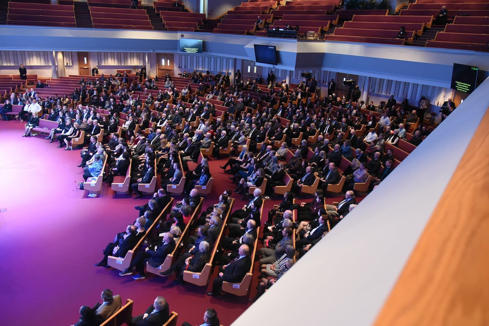 Attendees gather in a large auditorium for the memorial service of Don Young, filling the tiered seating of the venue.