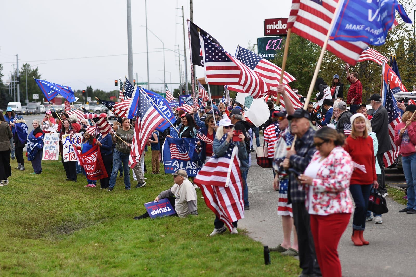 Supporters gather with American flags and campaign signs during a pro-Trump rally held in midtown Anchorage on a cloudy August afternoon.