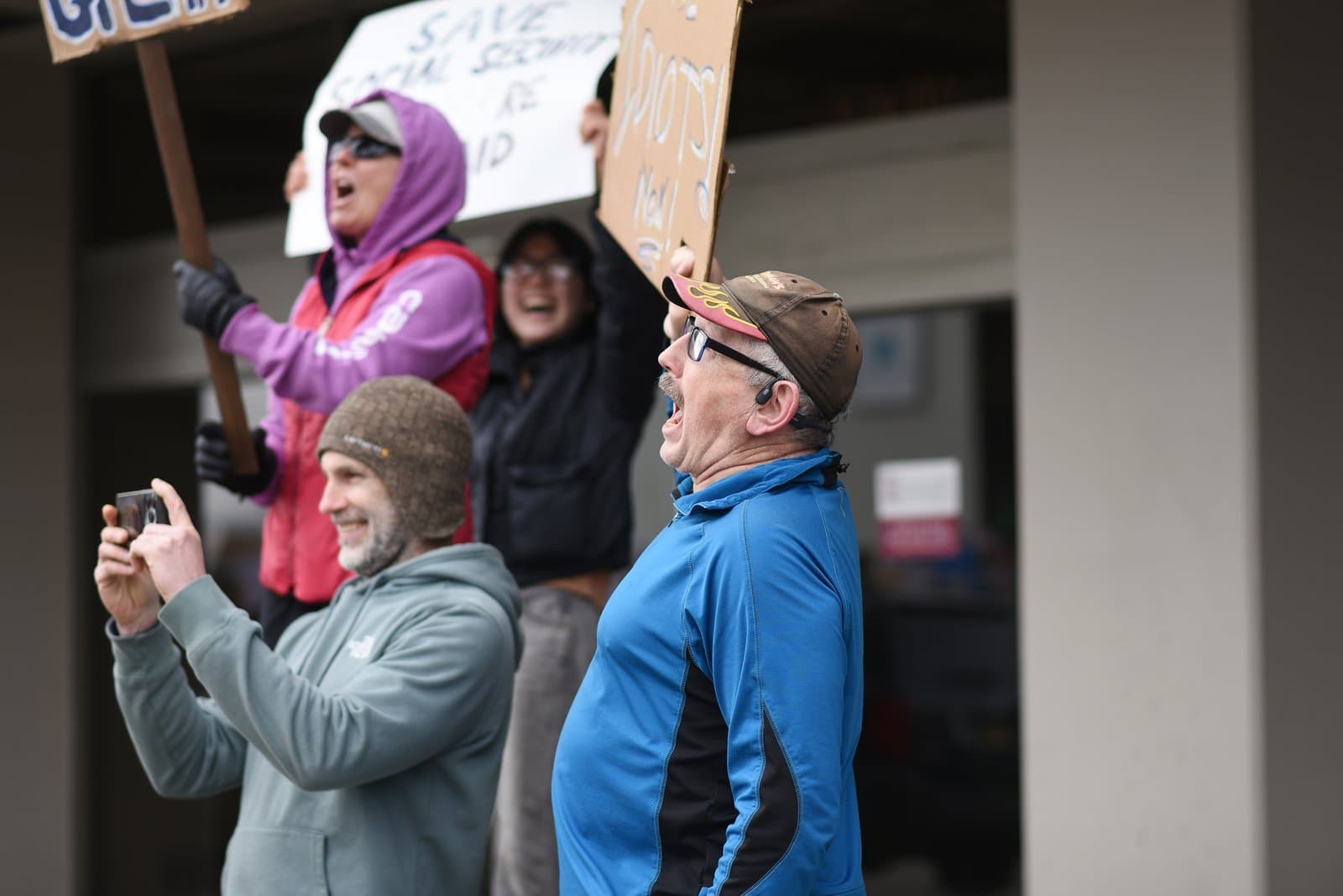 Protesters hold signs and shout during a demonstration in Anchorage, Alaska, on April 19, 2025, while one participant records the event.