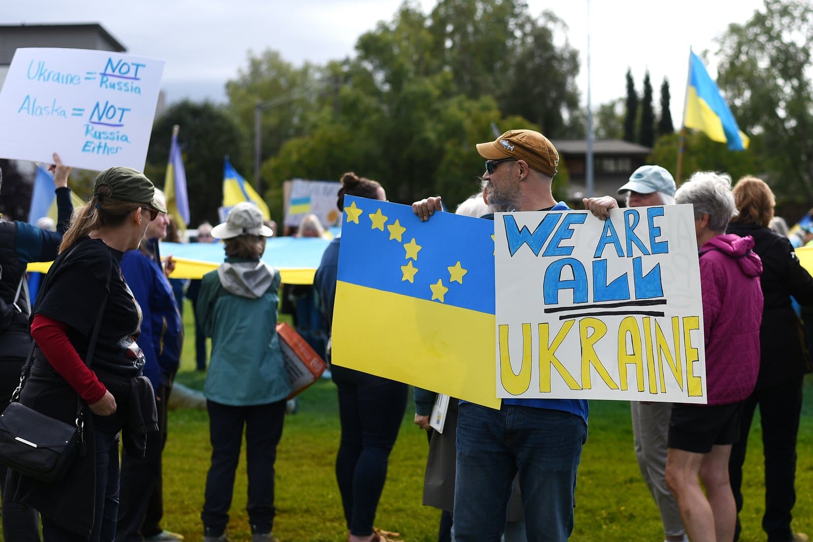Protesters gather in downtown Anchorage holding signs and a large Ukrainian flag during a demonstration on August 15, 2025.