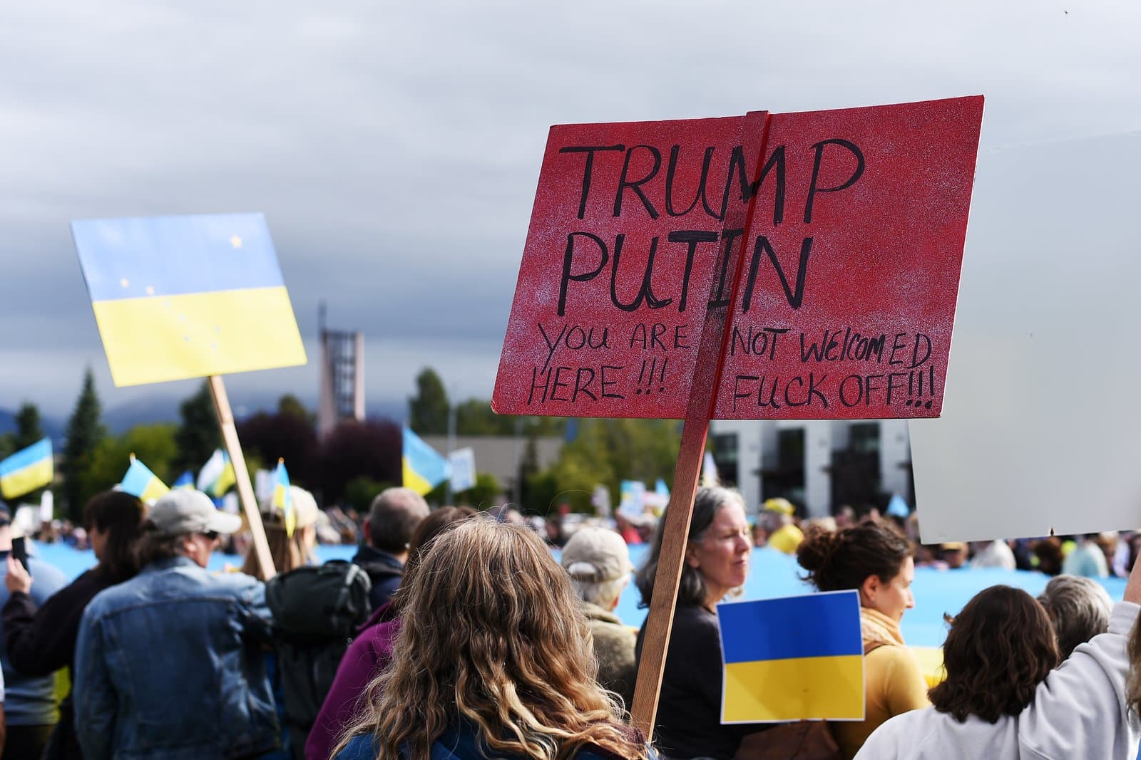 Protesters hold signs and Ukrainian flags during a demonstration in downtown Anchorage, Alaska, on August 15, 2025.