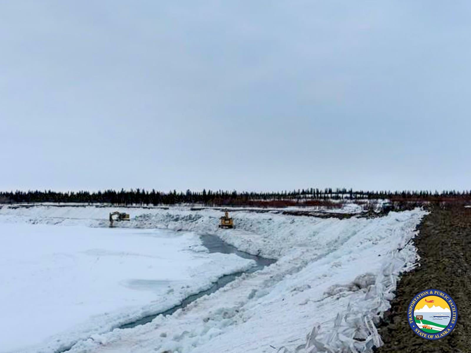 Two excavators work to clear ice along a riverbank in Noatak, Alaska, during the spring breakup season.