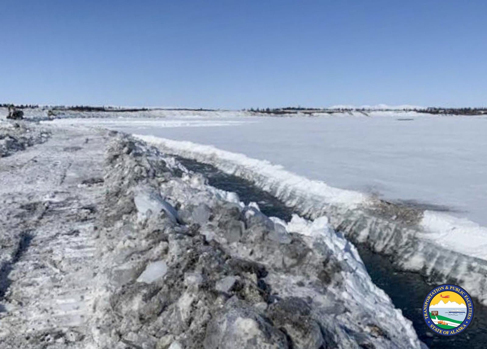 A channel of open water cuts through the frozen, snow-covered Noatak River during the spring breakup in rural Alaska.